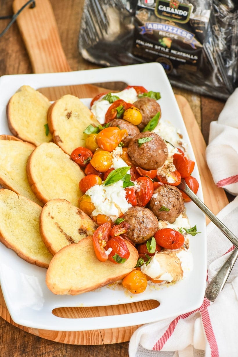 Roasted Tomatoes and Burrata on a plate with meatballs and crostini