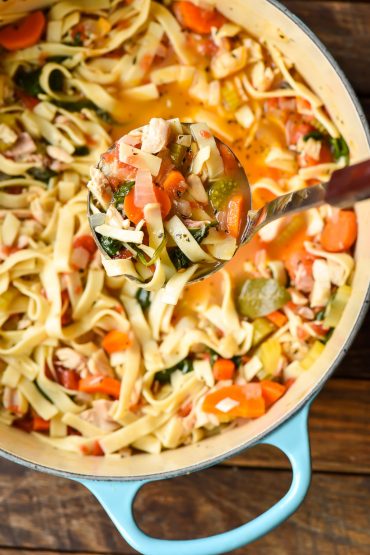 Ladle of Homemade Chicken Noodle Soup being taken out of dutch oven