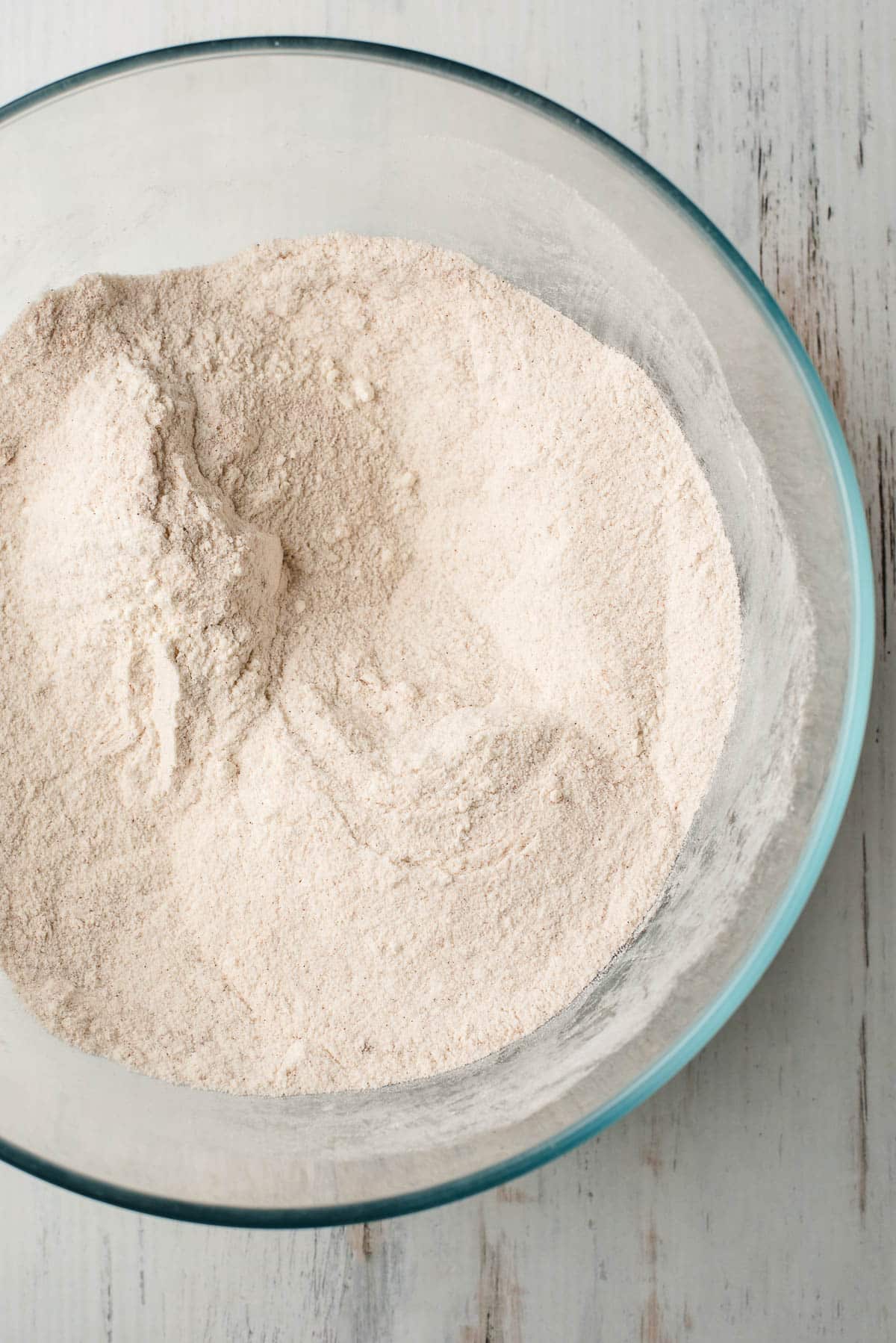 Flour, cinnamon, ginger, nutmeg, and cloves in a glass mixing bowl.