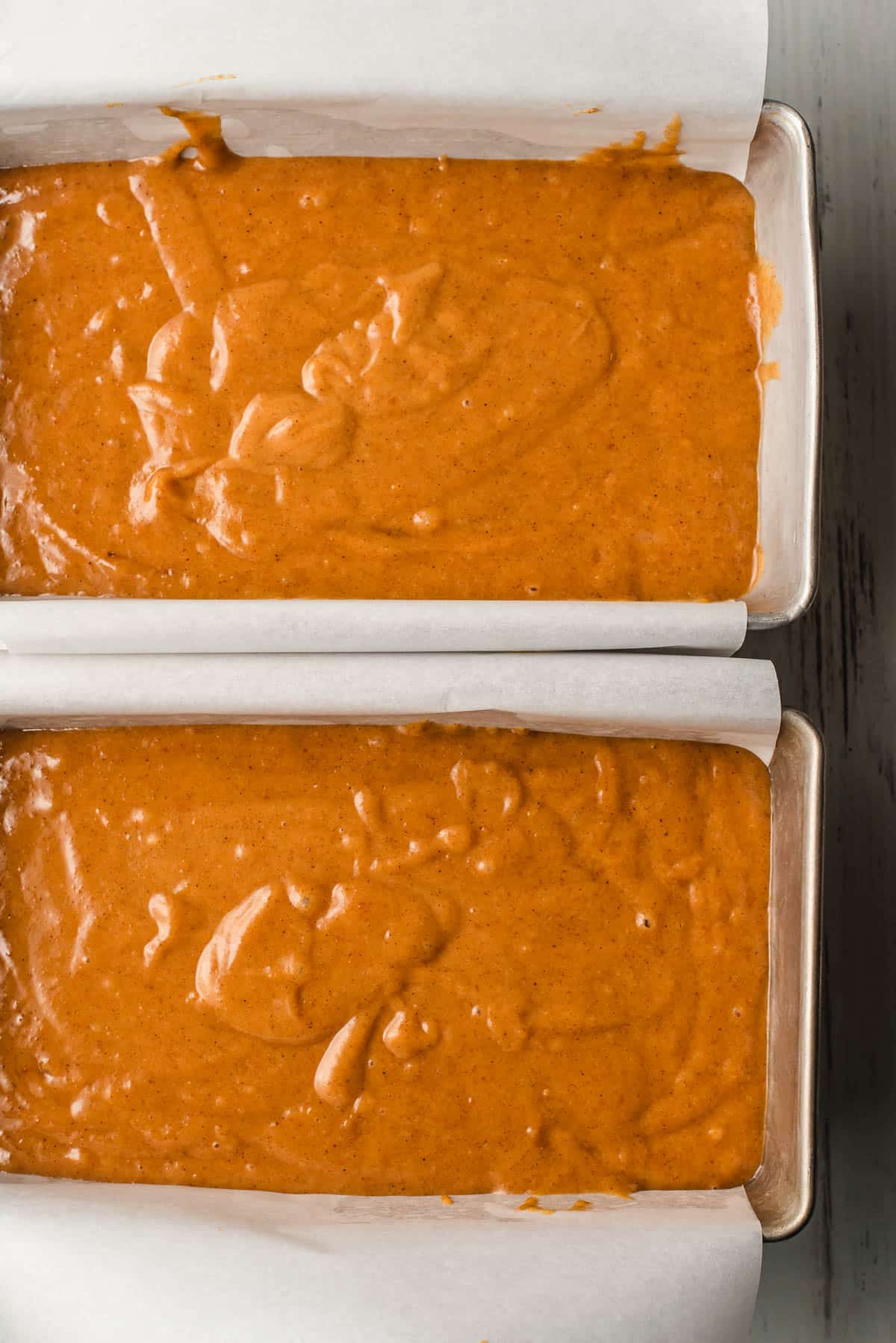 Two loaf pans filled with pumpkin batter.