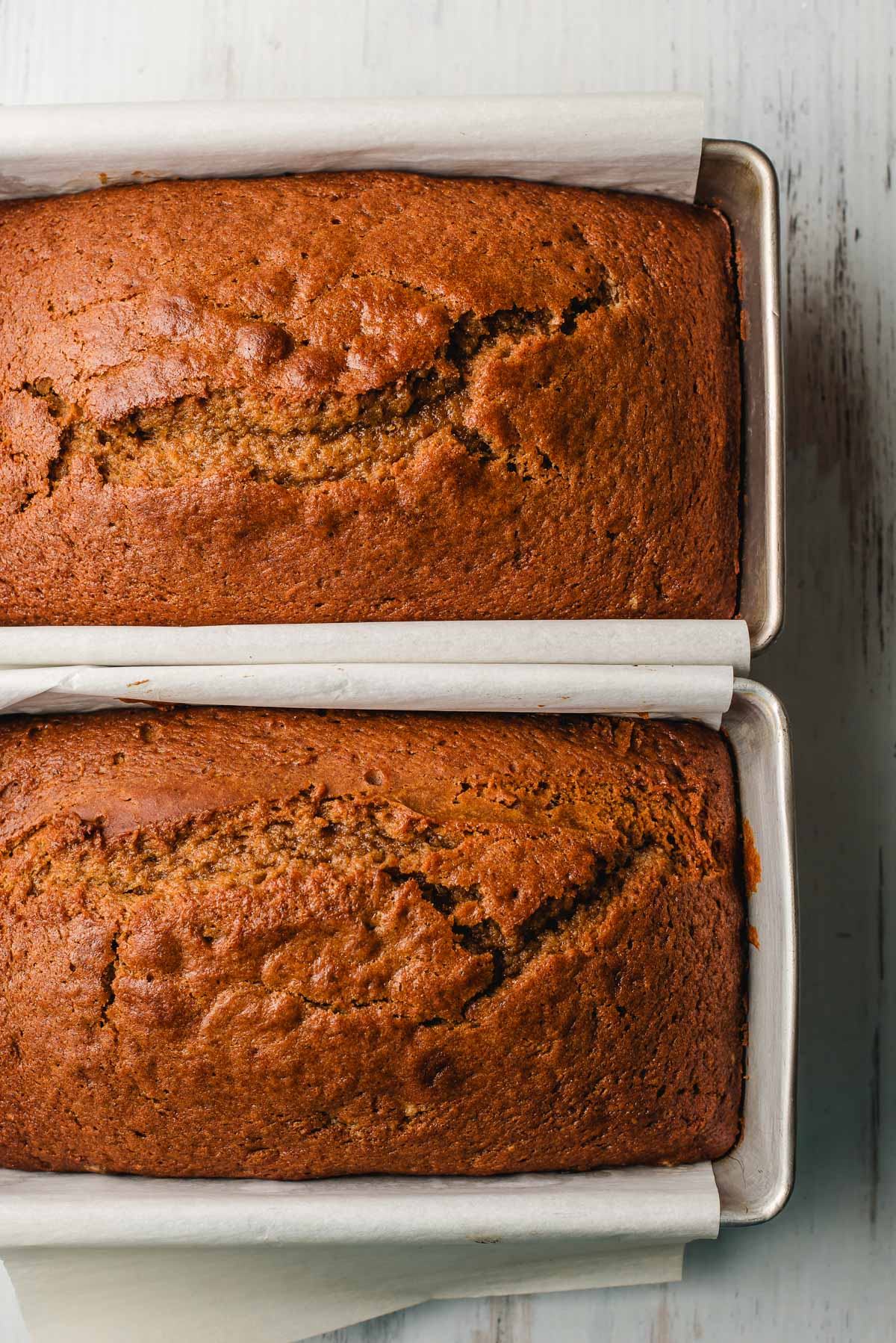 Two freshly baked loaves of pumpkin bread in loaf pans.