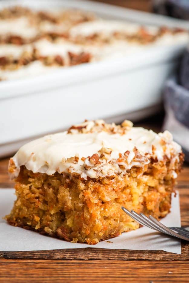 Carrot Sheet Cake slice with cream cheese frosting and pecans sprinkled on top.