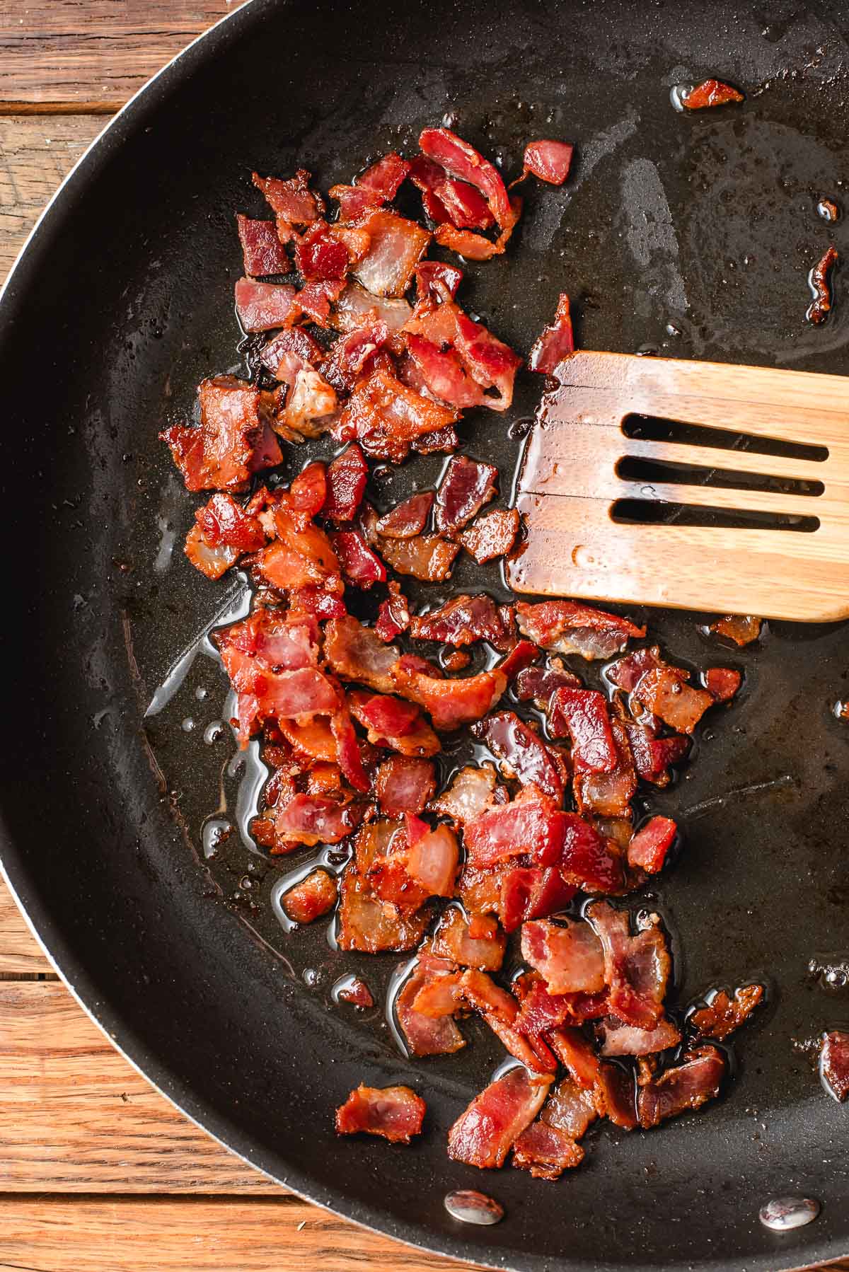 Cooked bacon bits in a skillet.