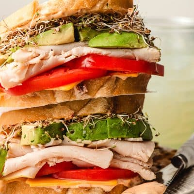 Two turkey avocado sandwiches stacked on top of each other.