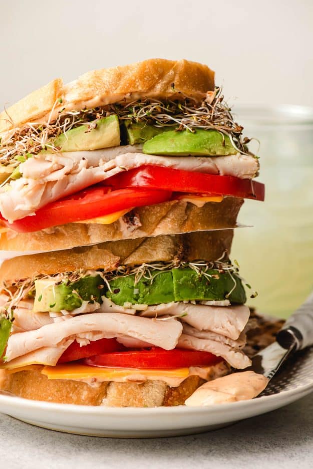 Two turkey avocado sandwiches stacked on top of each other.