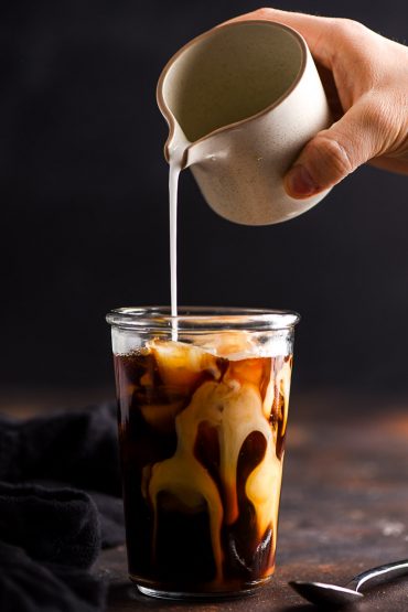 coconut milk poured into a glass of vanilla iced coffee