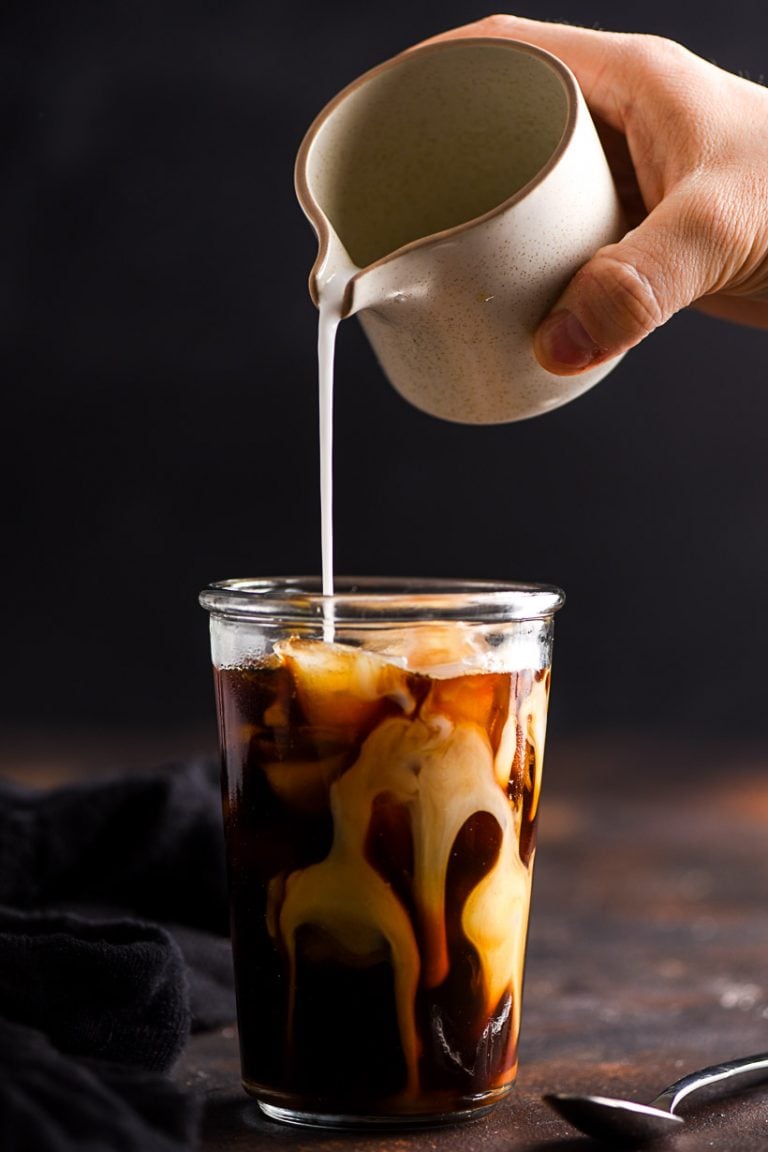 coconut milk poured into a glass of vanilla iced coffee
