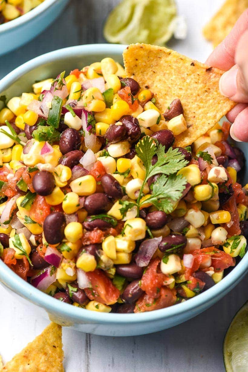 Bowl of Black Bean and Corn Salsa with Tortilla Chip dipping into it