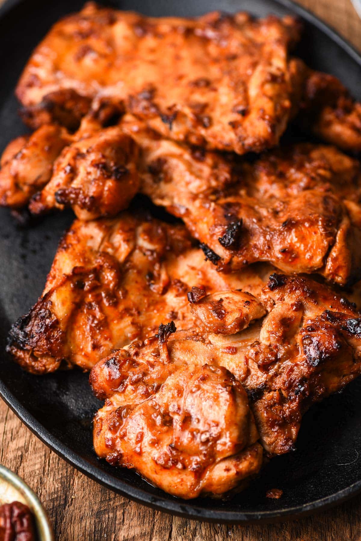 Grilled Spicy Chicken Thighs on a black platter.