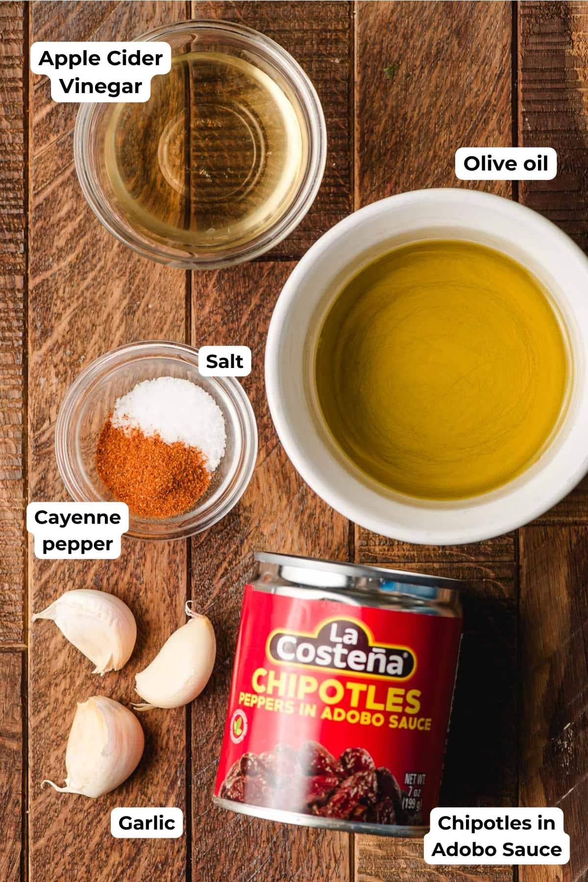 Apple cider vinegar, olive oil, cayenne pepper, salt, garlic, and canned chipotles in adobo in bowls.