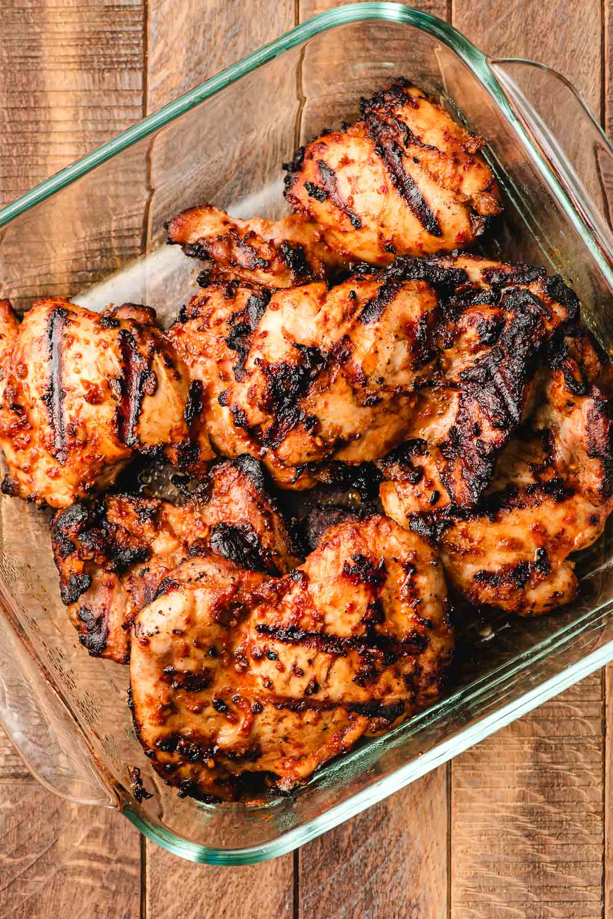 Grilled chicken with spicy marinade in glass container.