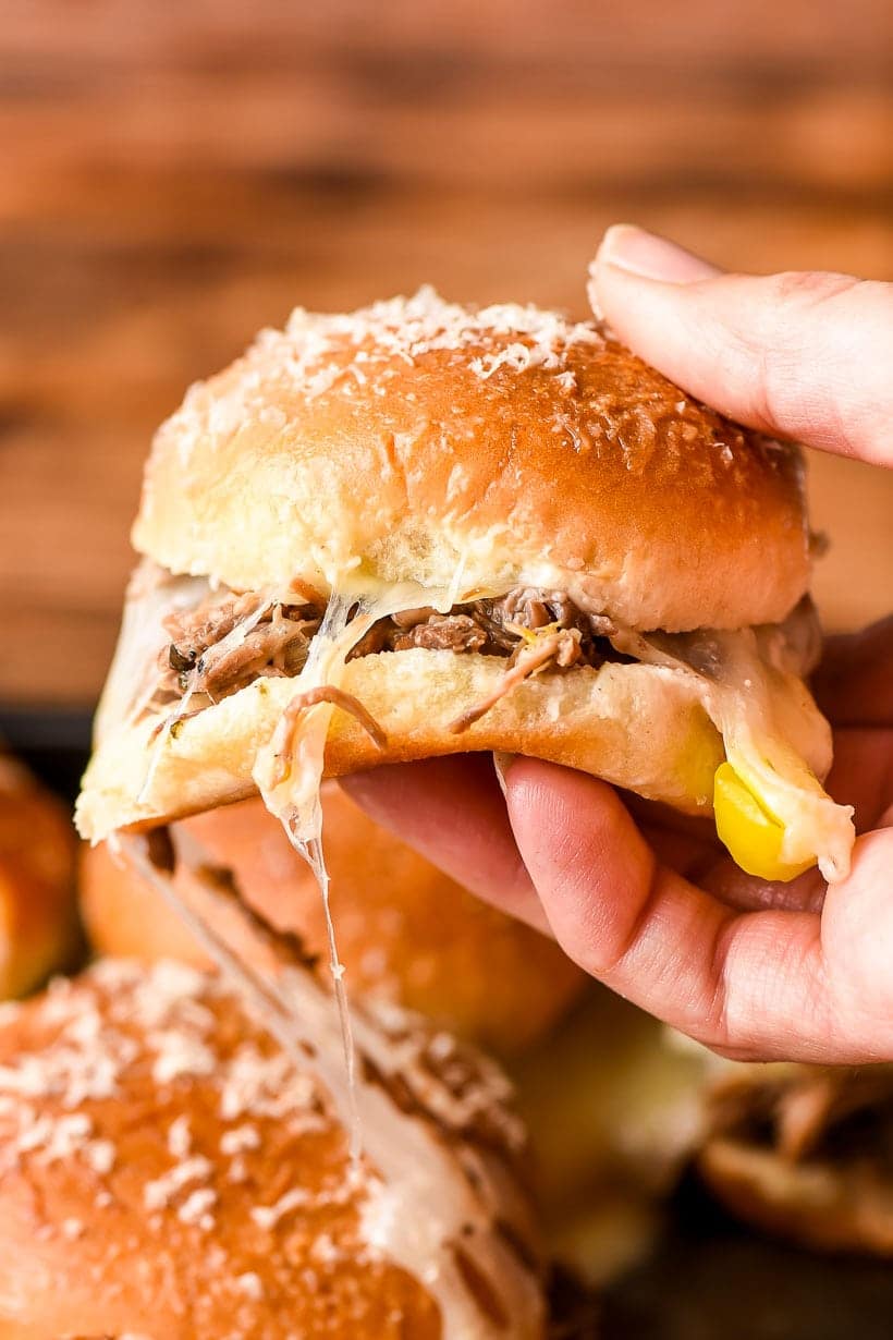 a hand holding a cheesy roast beef slider
