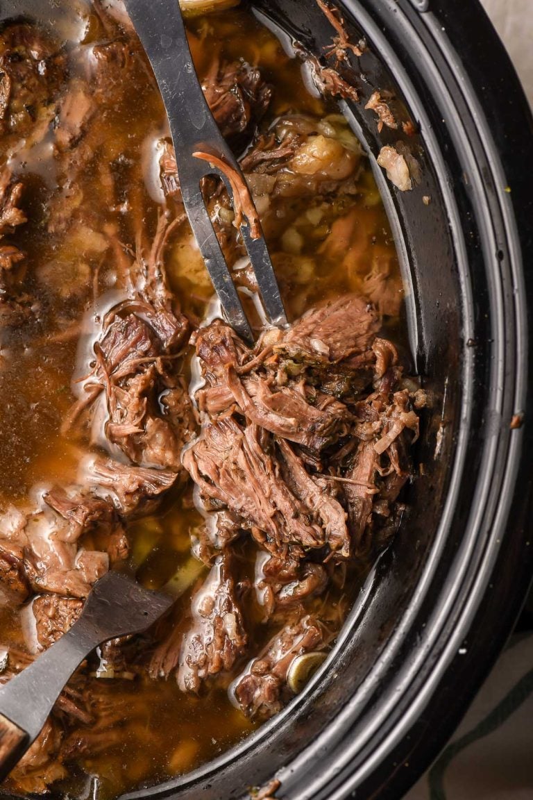 Meat fork stabbing into pulled beef in a crock pot