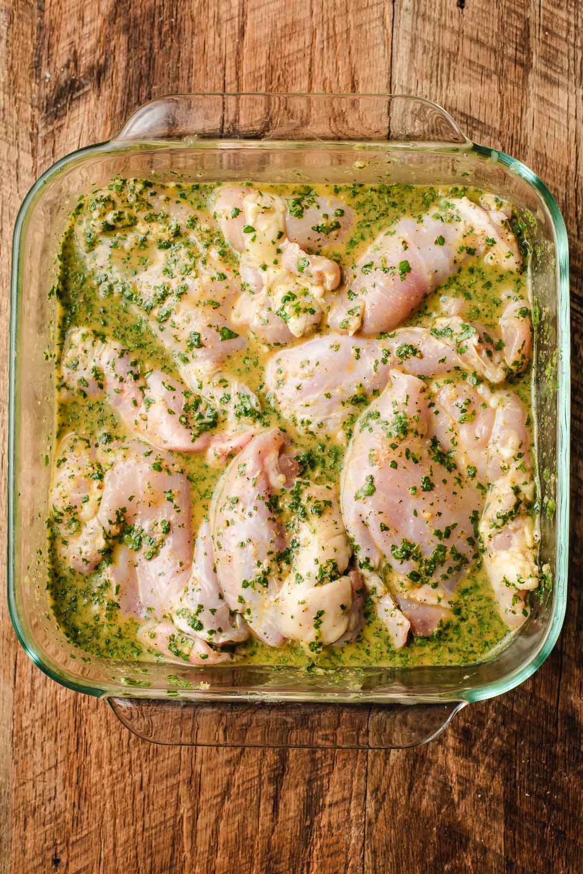 Chicken thighs in a cilantro lime marinade in a glass dish.