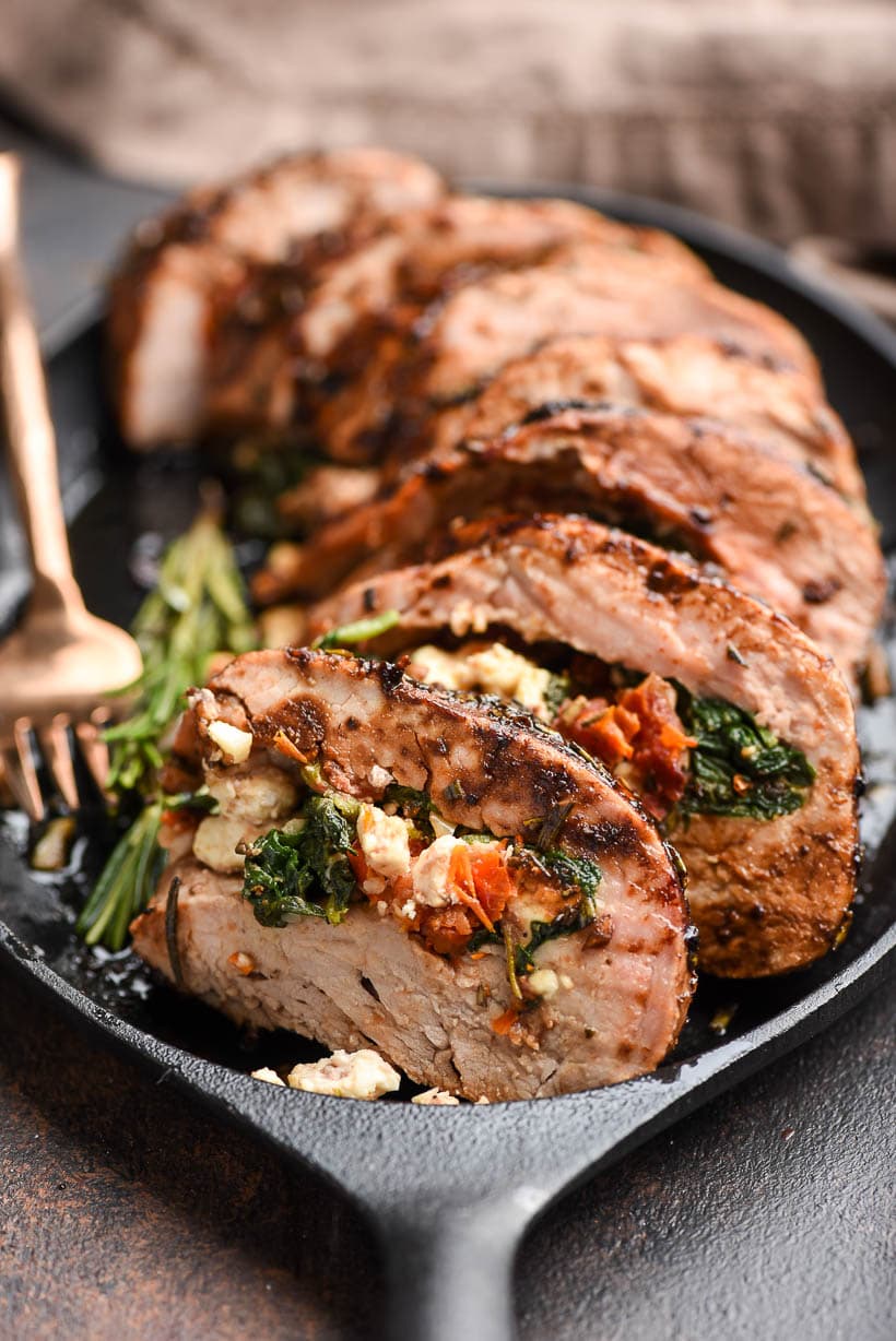 Juicy stuffed pork tenderloin filled with mediterranean herbs and cheese served on a skillet