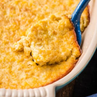 corn souffle in an oval casserole dish with blue scoop