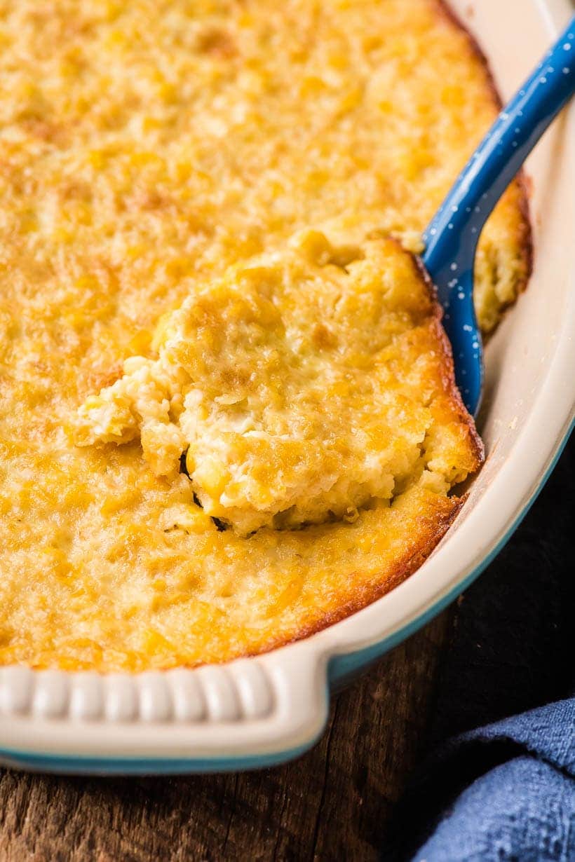 corn souffle in an oval casserole dish with blue scoop