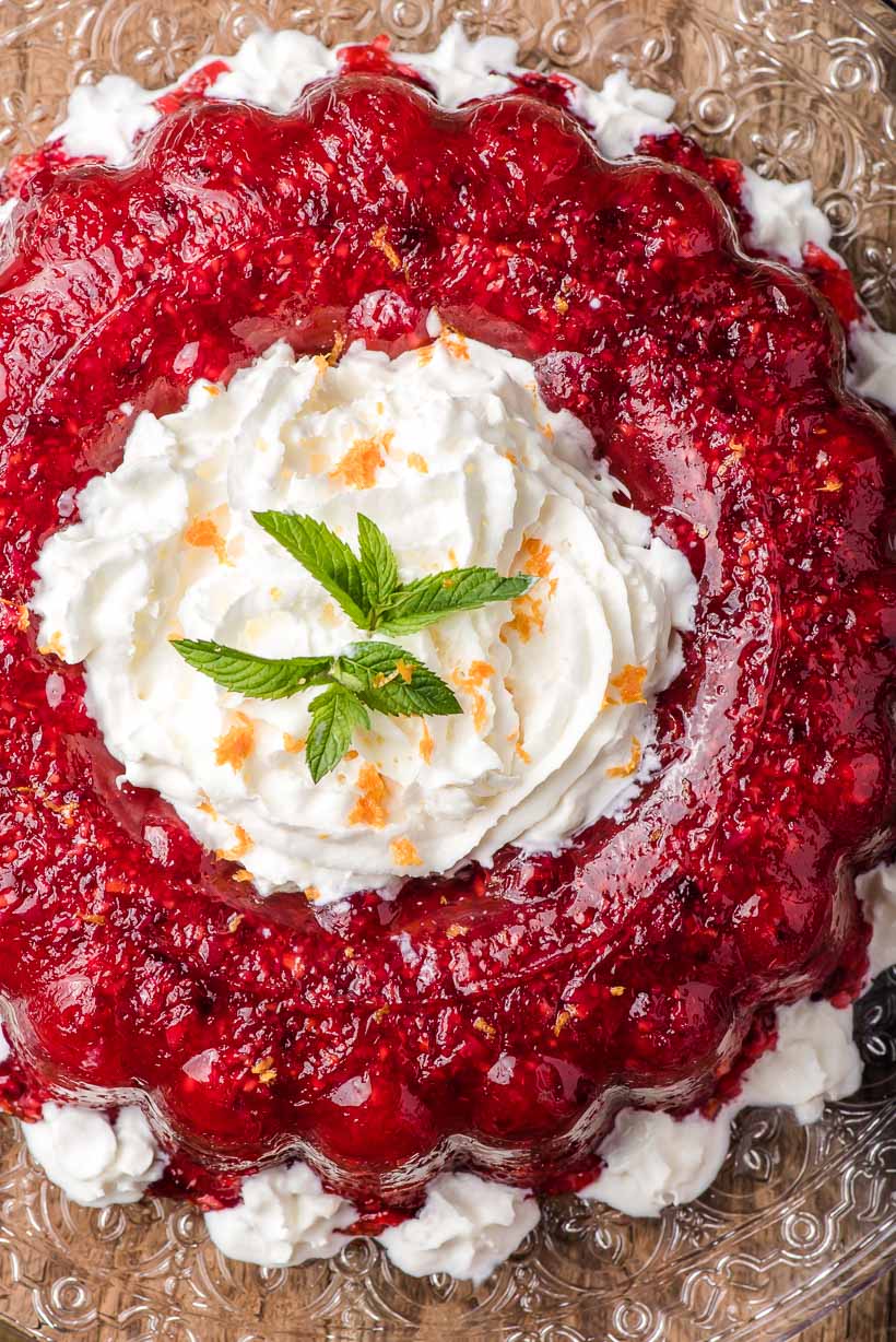 overhead shot of cranberry jello salad with whipped cream and mint leaves