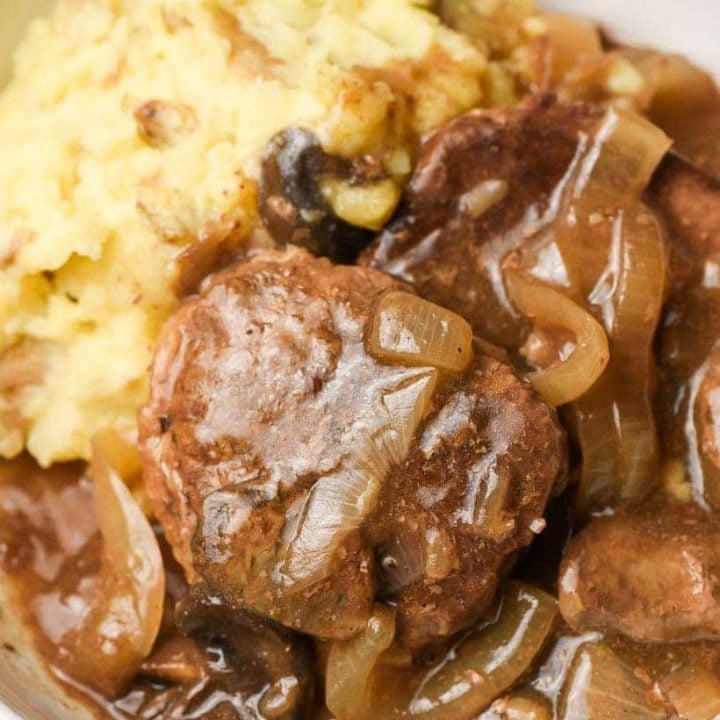 round steaks with gravy in a bowl with mashed potatoes