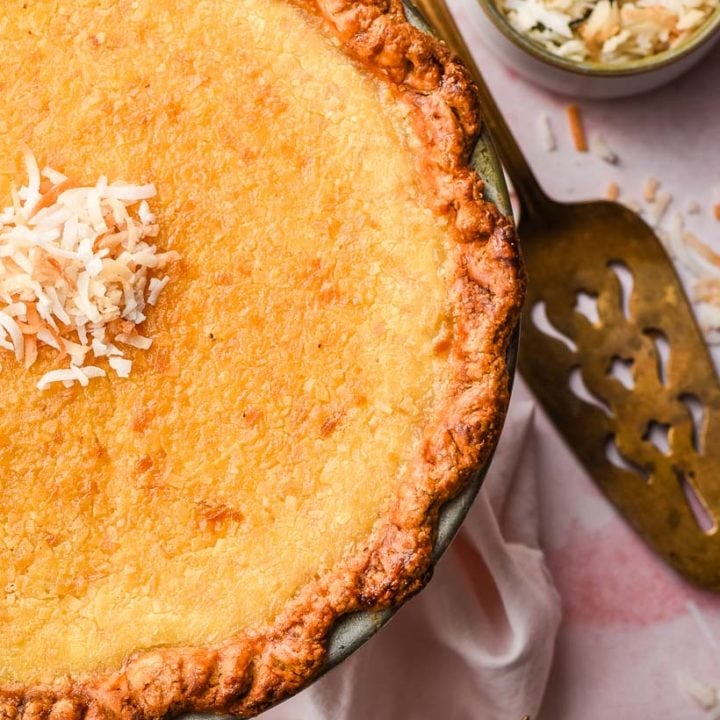 coconut custard pie with a gold pie server and flaked coconut