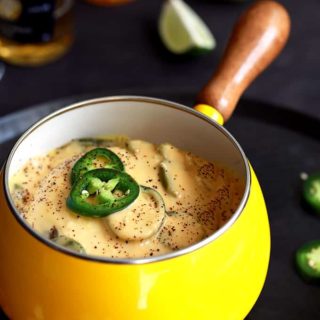 Mexican beer cheese fondue in a yellow pot.