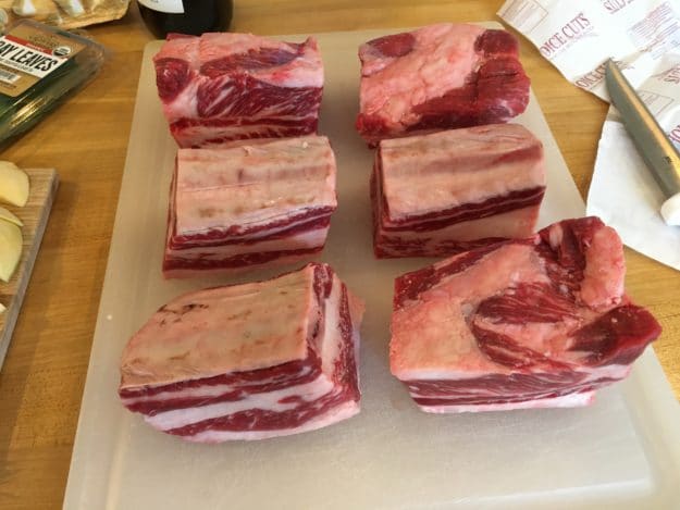 6 raw beef short ribs on a cutting board