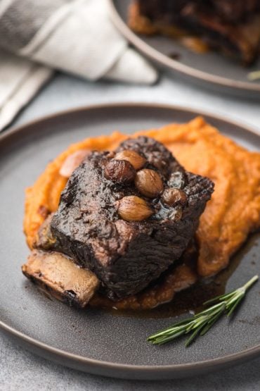 braised short rib with root vegetable puree on a dark gray plate