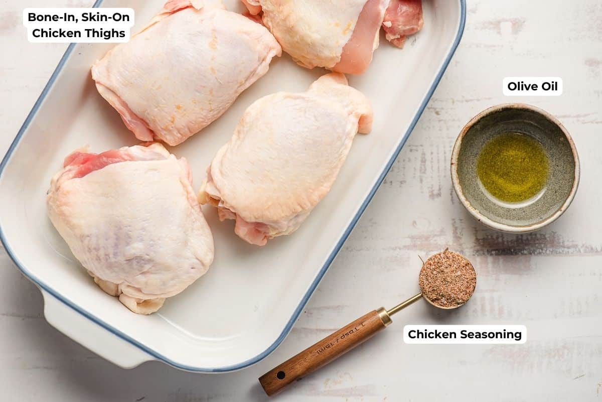 Bone in, skin on chicken thighs, a measuring spoon of chicken seasoning, and bowl of olive oil.