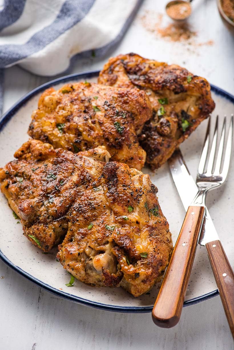 air fryer chicken thighs on a plate with a knife and fork