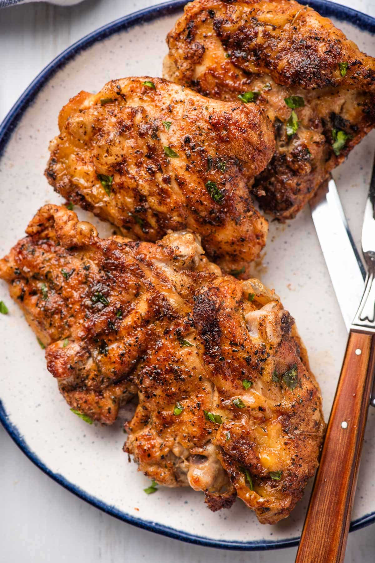 Air fried chicken thighs on a white plate with a blue rim.