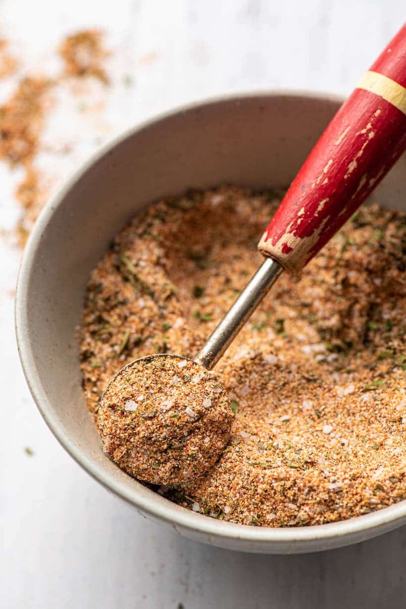 chicken seasoning being scooped out of a bowl