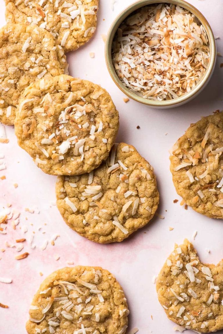 coconut cookies with flaked toasted coconut on a pink background