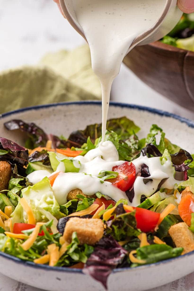 bowl of garden salad with ranch dressing poured on top