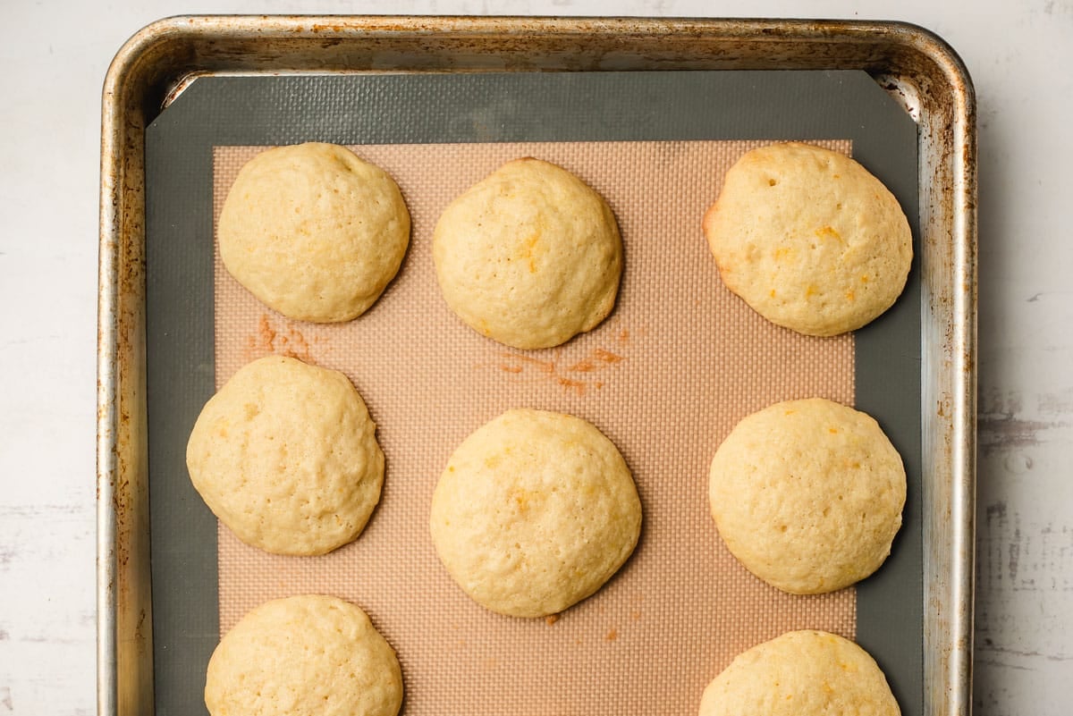 Freshly baked orange cookies on a baking sheet.