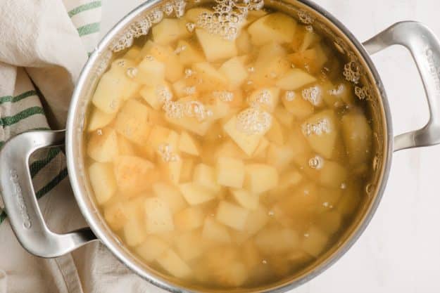 Large stock pot filled with diced potatoes and cold water.