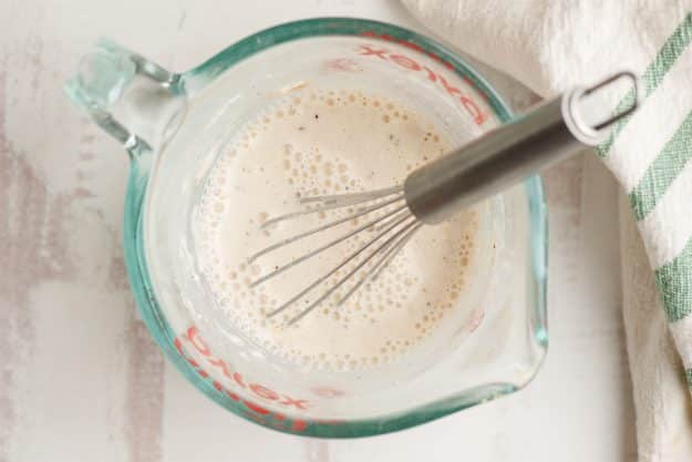 Flour, milk, salt, pepper, garlic powder, and dried parsley whisked together in a measuring cup.