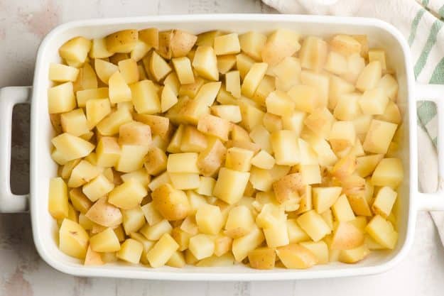 Cooked diced potatoes in a white casserole dish.