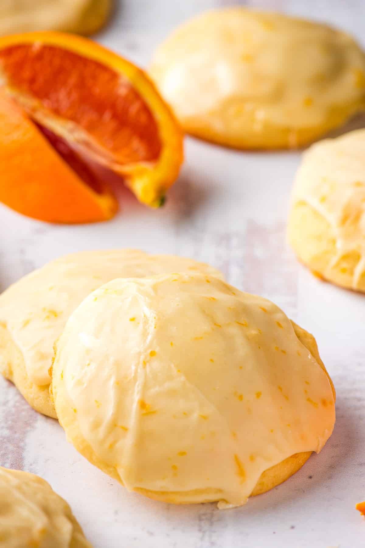 Several orange cookies set on a white background with blood orange slices in the background.