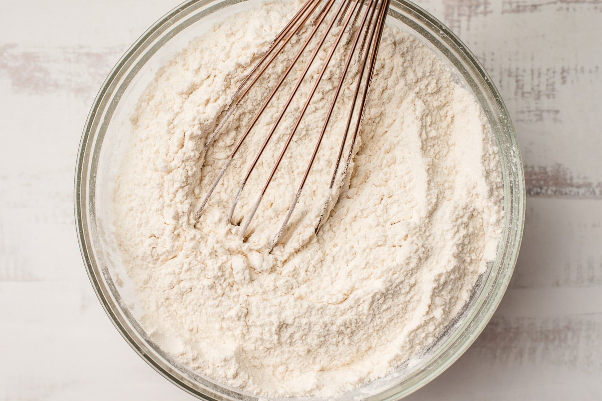 Flour, baking powder, baking soda, and salt whisked together in a glass mixing bowl.