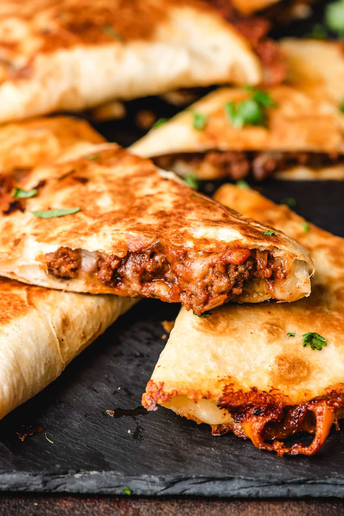 Slice of quesadilla with ground beef filling and cheese spilling out.