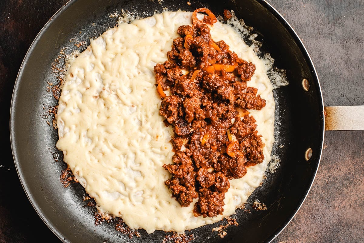 Ground beef filling layered on half of a cheesy tortilla.