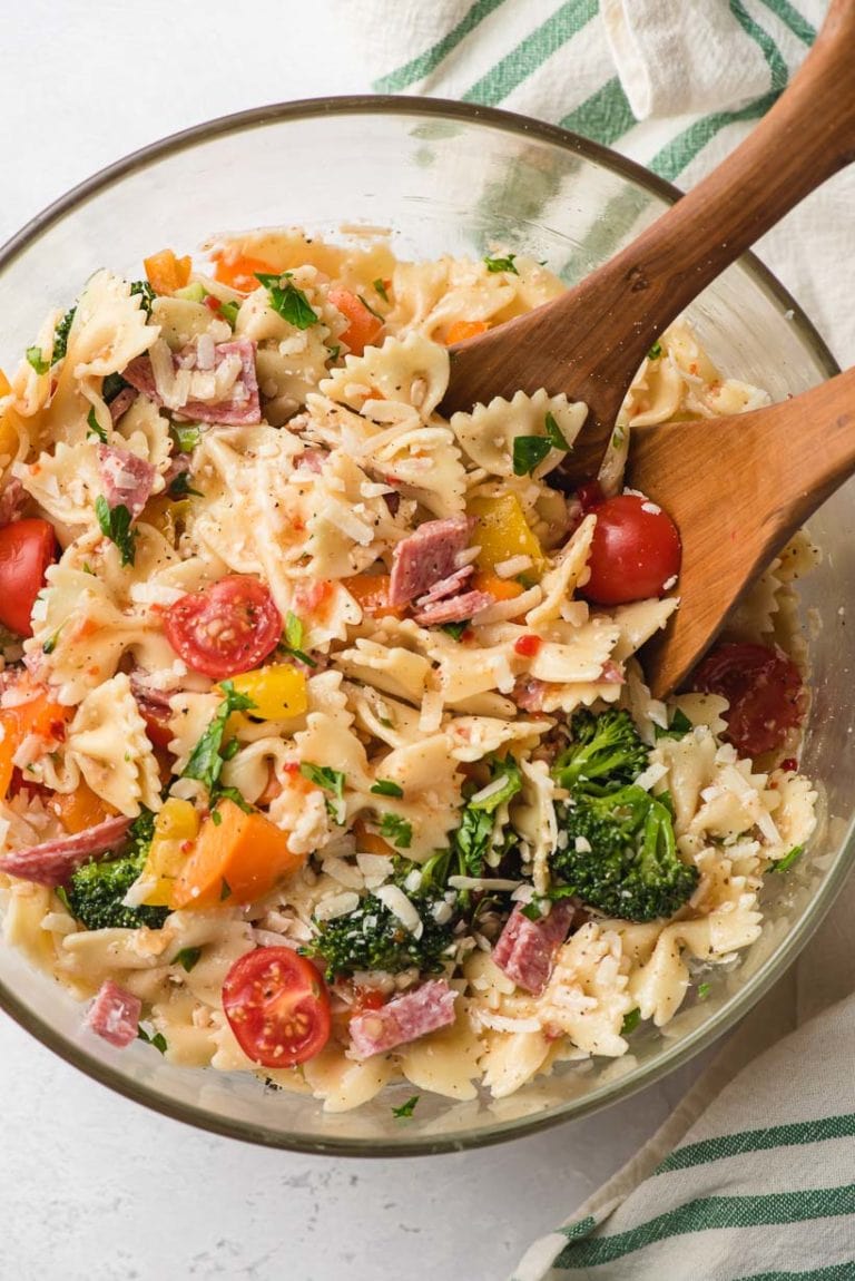bowtie pasta salad in a glass bowl with wood serving utensils