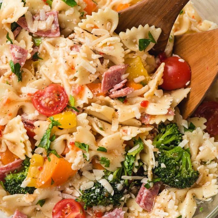 Italian bowtie pasta salad in a large bowl with wooden spoon