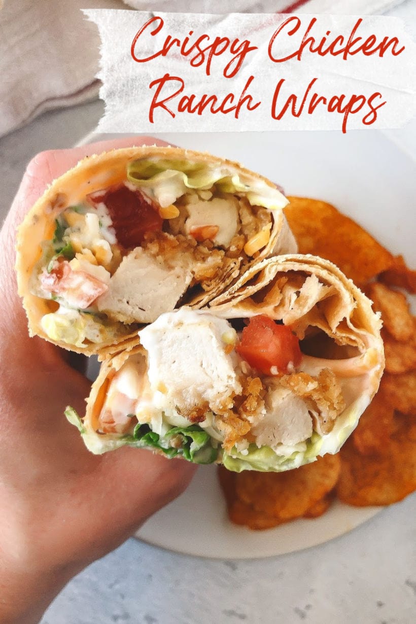 Hand holding two halves of a crispy chicken ranch wrap