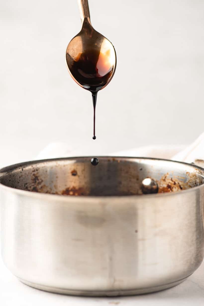 balsamic reduction dripping off a spoon into a sauce pot