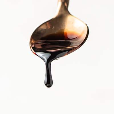 Balsamic reduction dripping off of a golden spoon.