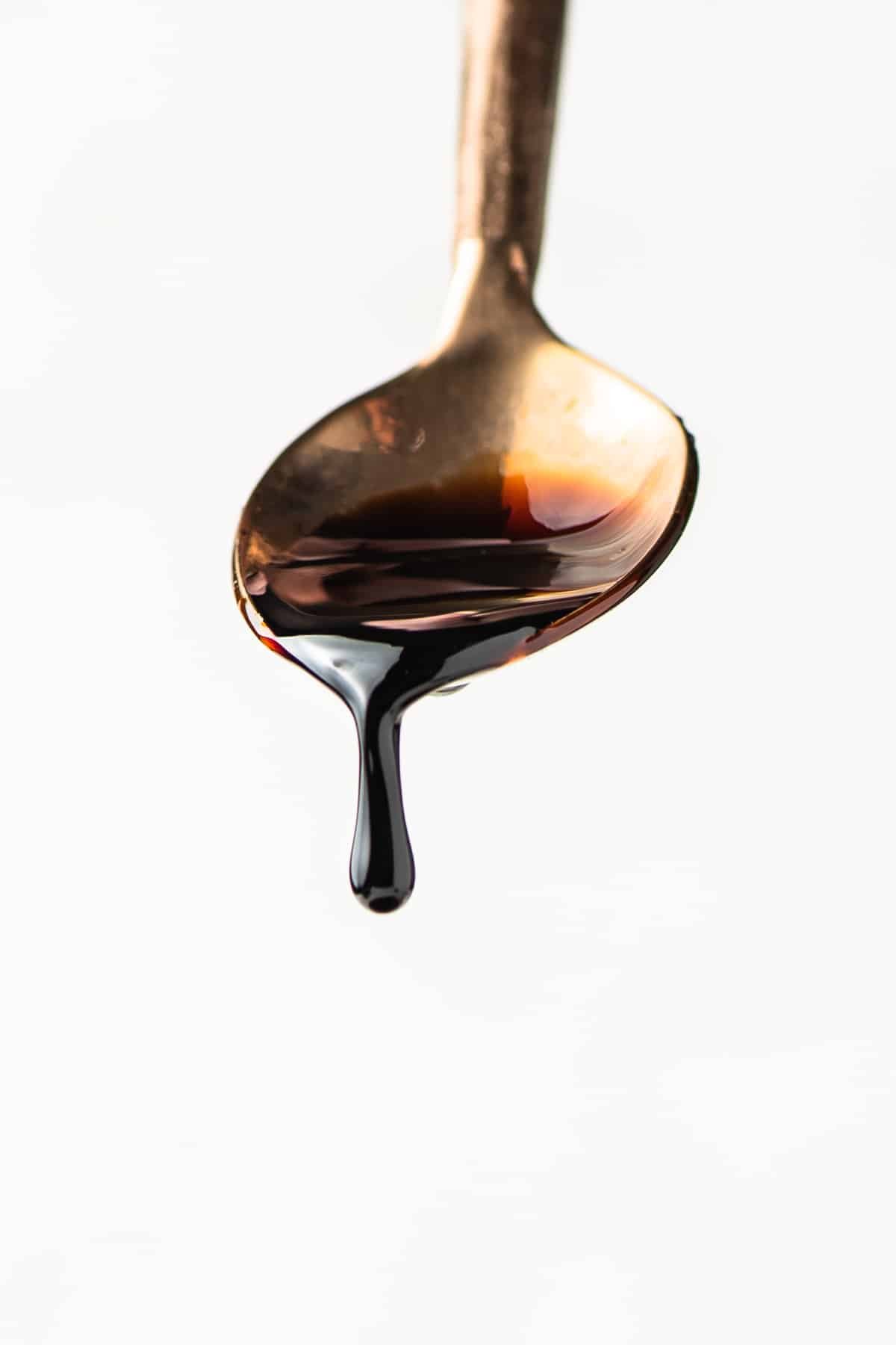 Balsamic reduction dripping off of a golden spoon.