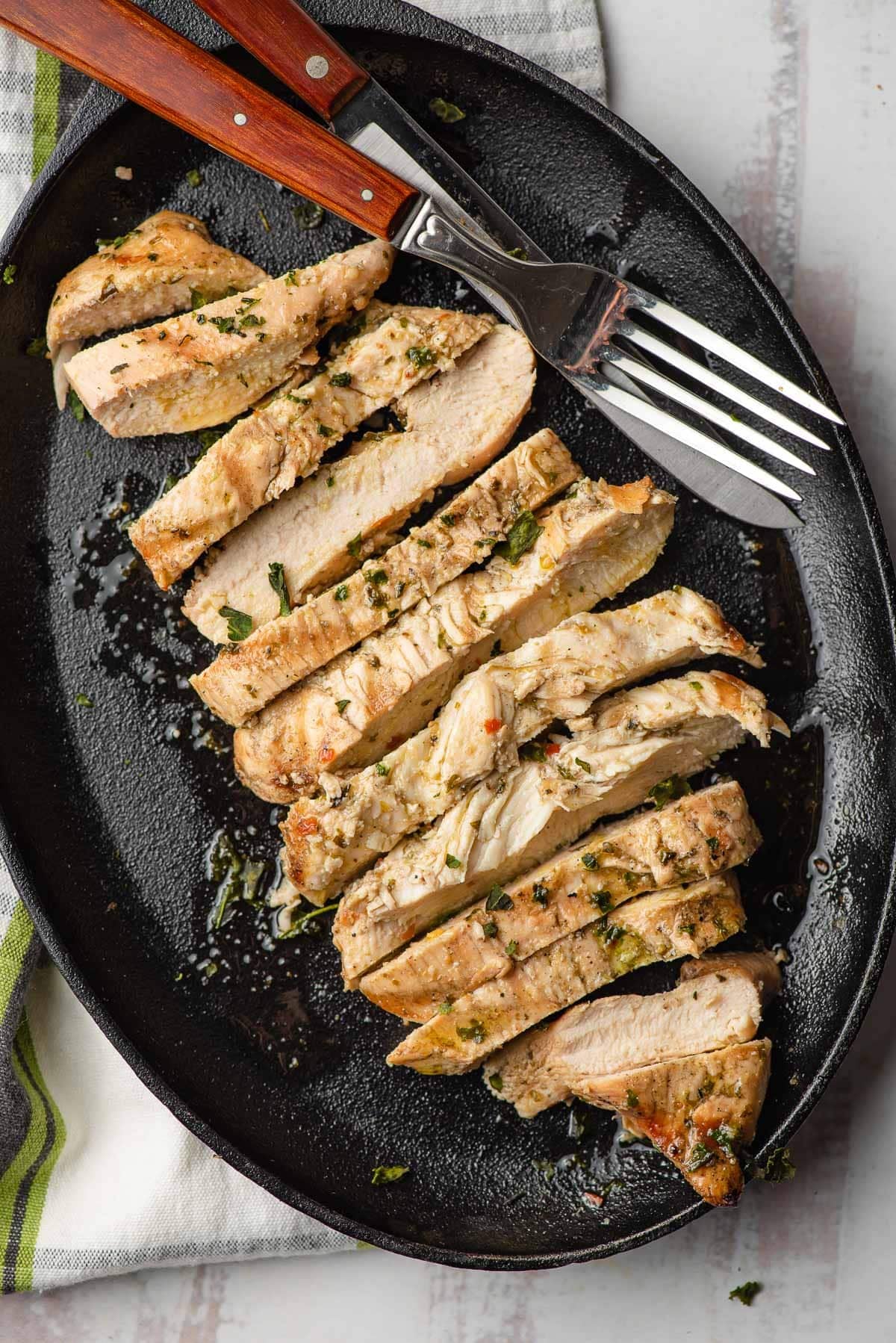 Sliced Italian dressing chicken on an oblong cast iron skillet.