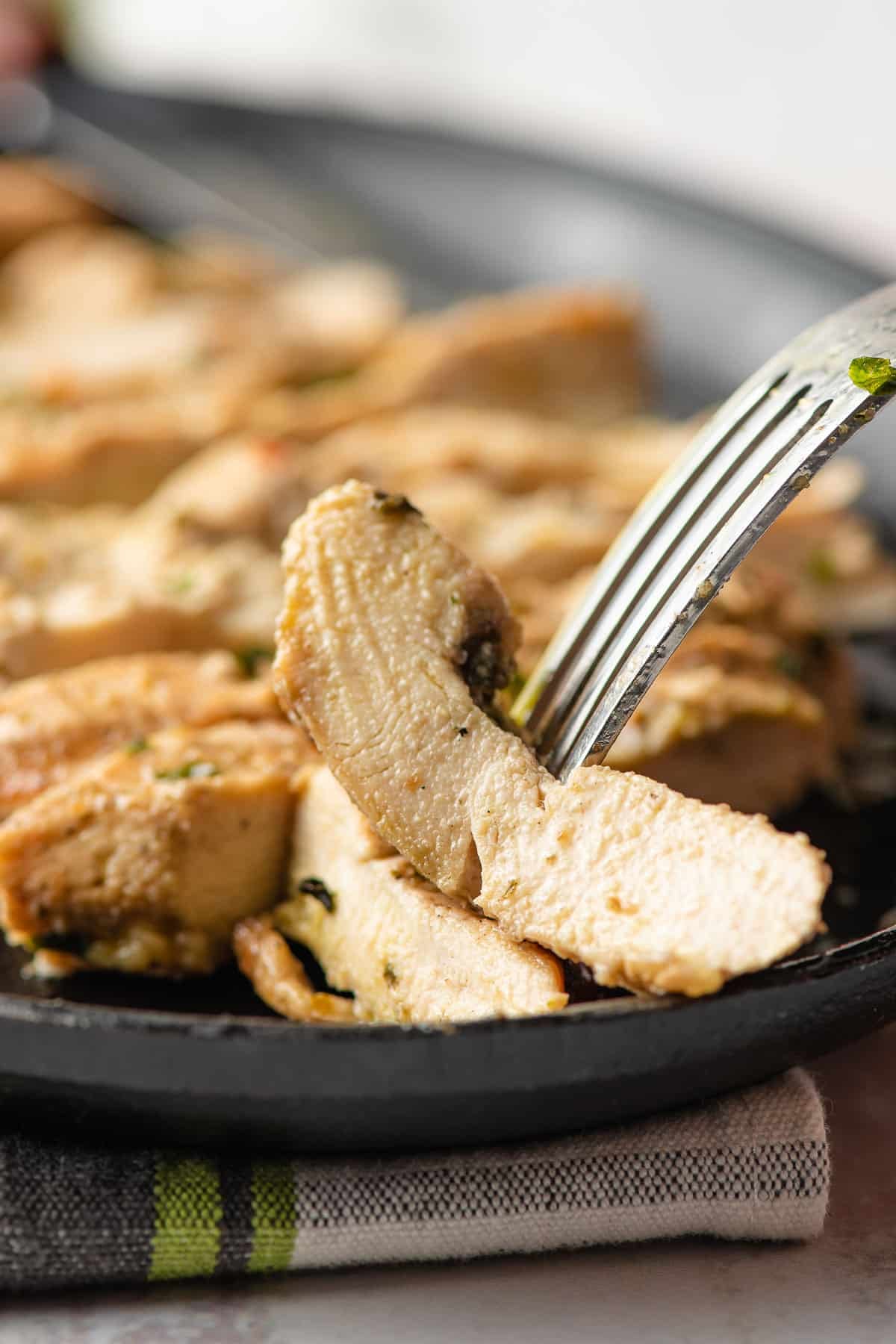 Fork picking up a slice of Italian marinated chicken.