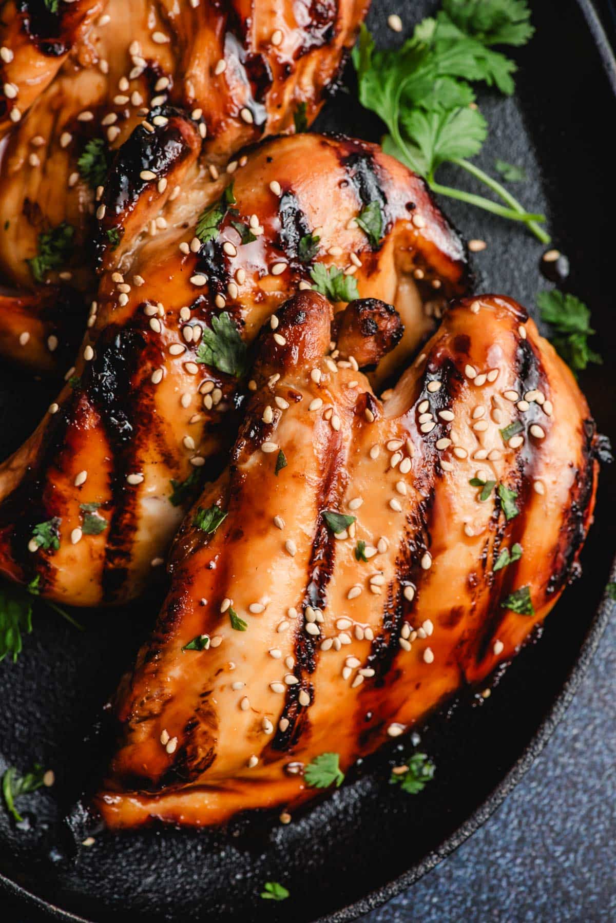 Grilled Asian Chicken breasts on a black cast iron skillet.